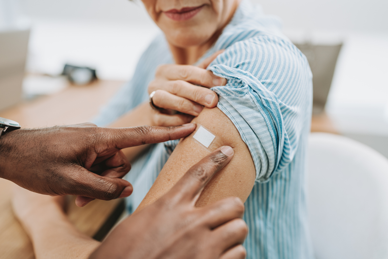 Provider applying a bandaid over a patient's shingles vaccine