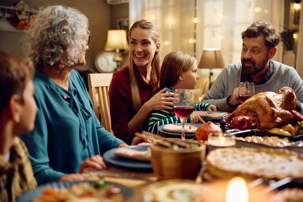 Happy extended family talking while having dinner at dining table on Thanksgiving